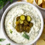 Dill pickle dip with cottage cheese served in a bowl with fresh dill